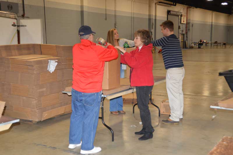 American Legion Post 3 Member Ed Brannen and volunteers from General Electric to tap up boxes that will hold the non-perishable food items.