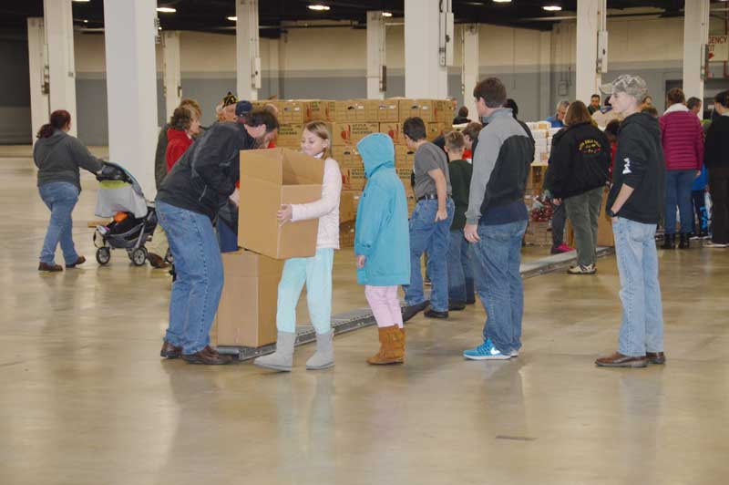 A female volunteer picks up a Goodfellows Food Box to take to the storage area.