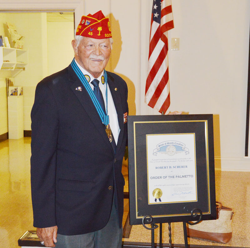 Bob Scherer stands beside his Order of the Palmetto. The highest award presented to a civilian by the State of South Carolina.